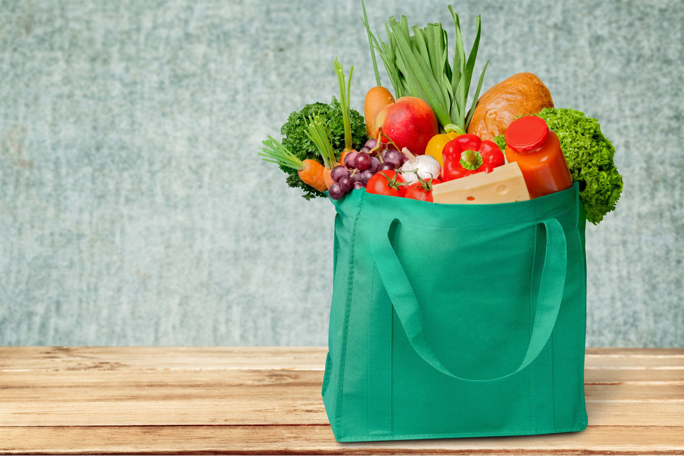 green reusable tote bag filled with groceries
